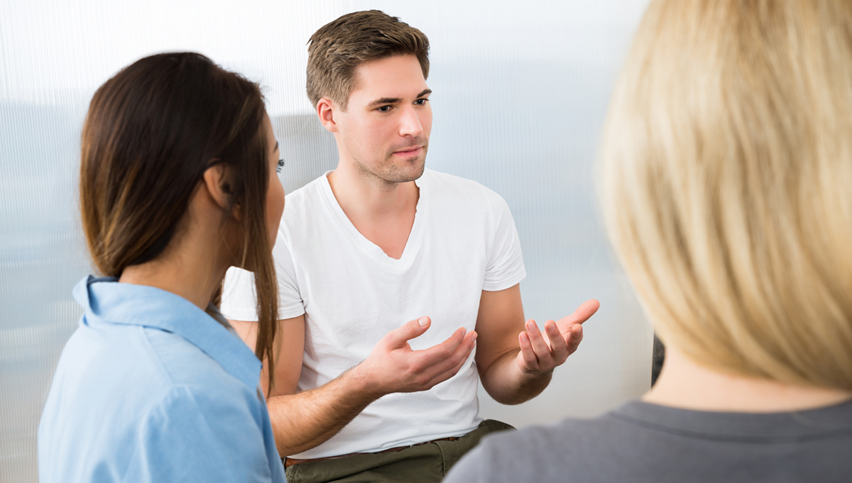 Tre personer sitter och pratar med varandra i ett gruppsamtal så som personal och brukare gör med hjälp av delaktighetsmodellen.