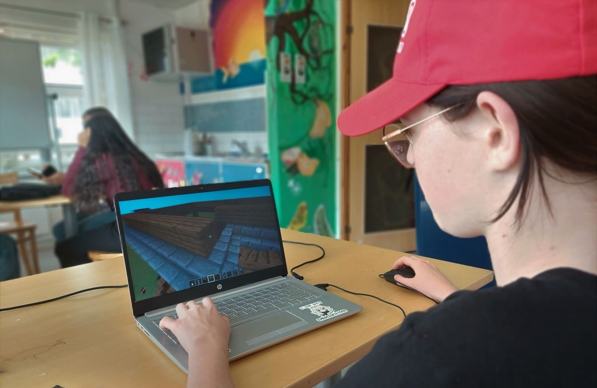 Ungdom spelar Minecraft på laptop, foto