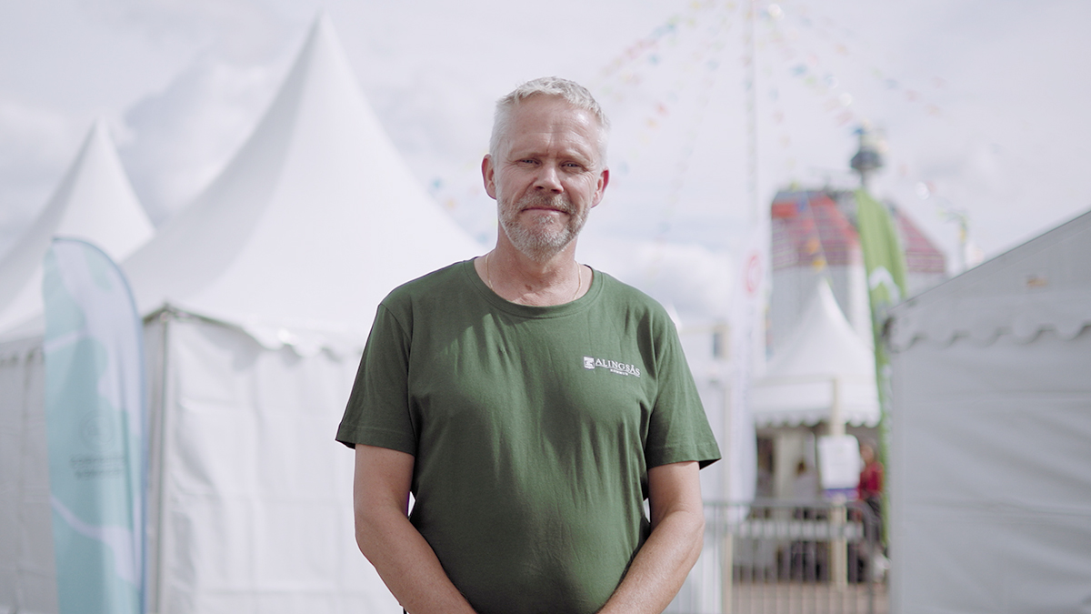 Christer Johansson, med kortklippt grått hår och skägg, står i grön tröja framför några vita tält på Frihamnsdagarna i Göteborg.